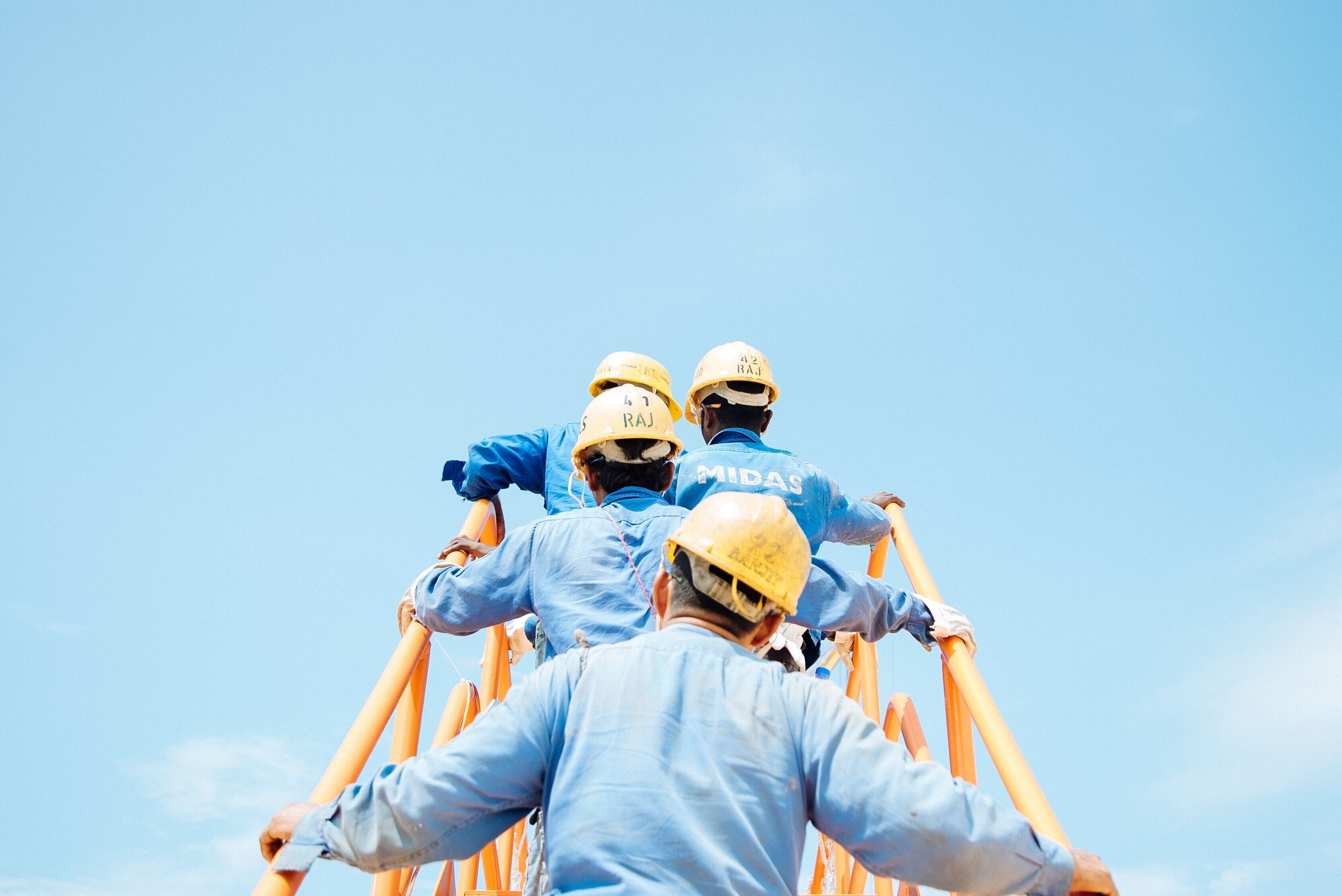 Construction workers heading up a yellow constructions staircase: Companies with private equity ownership employ 12 million people in the United States.