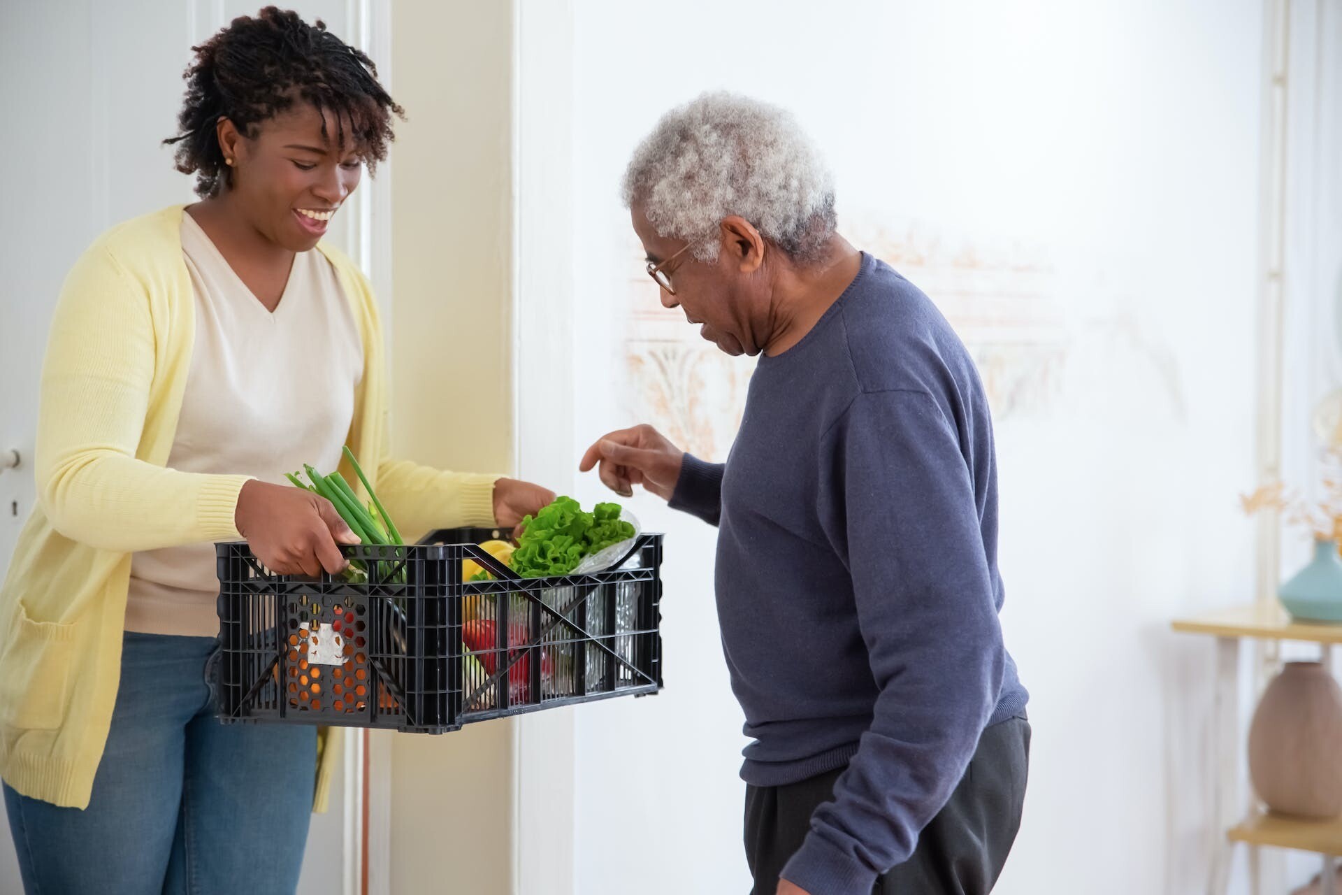 A woman holding a plastic crate with fruits and vegetables, illustrating healthy habits. Life insurance is important for the elderly as well as younger generations.